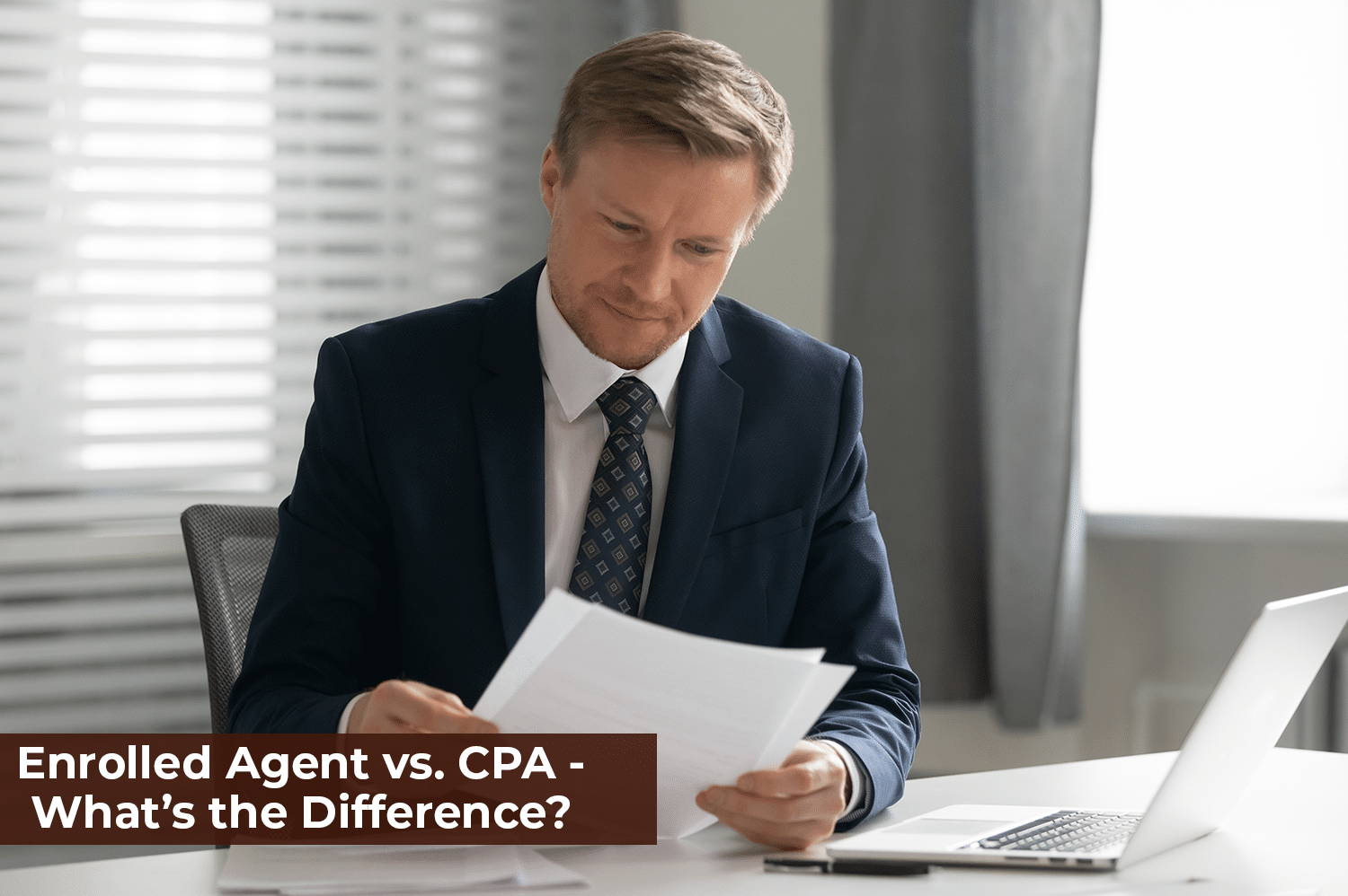 An enrolled agent working at his desk, looking at paper in his hands.