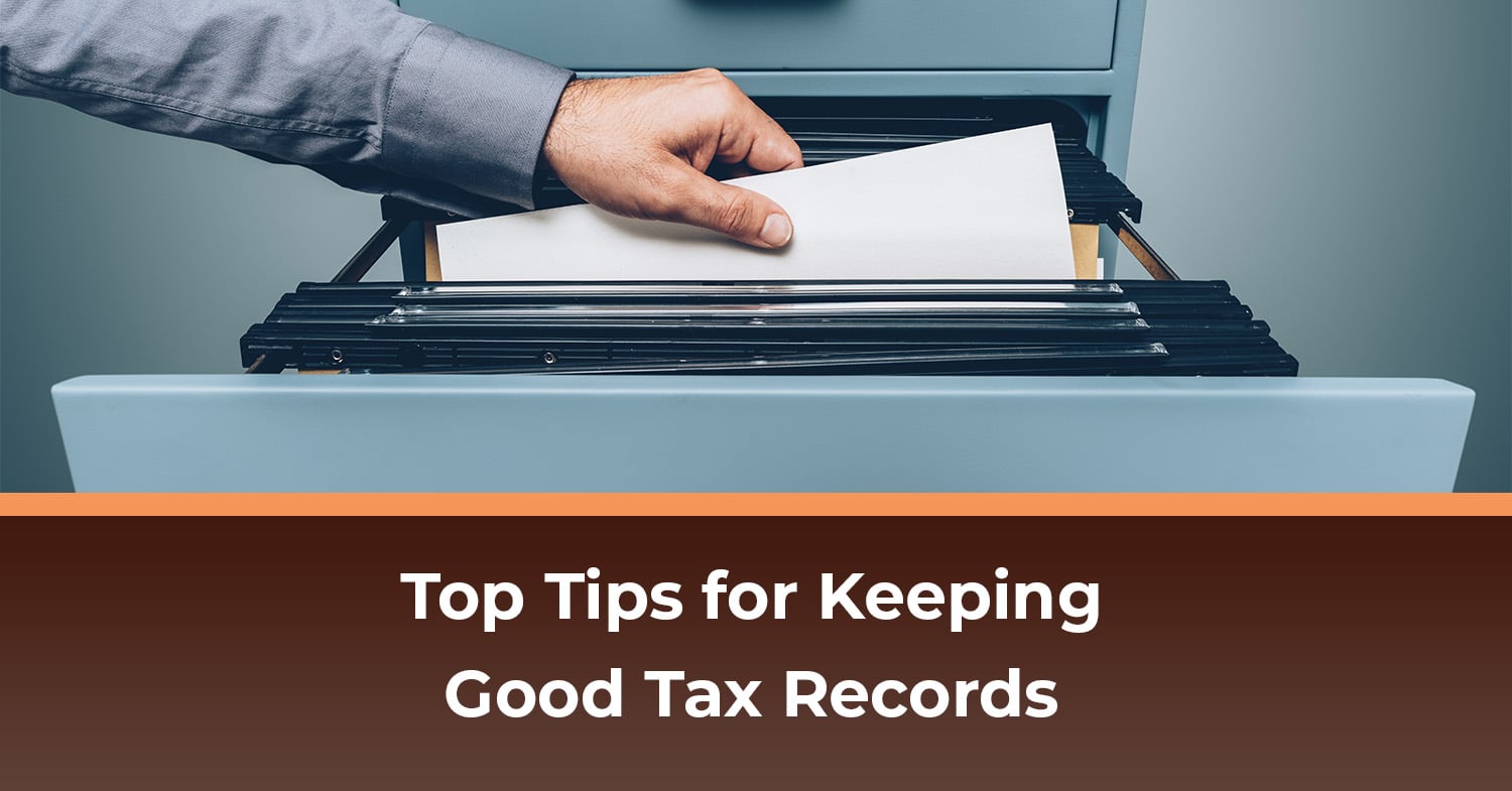 A person reaching into their tax records in a filing cabinet.